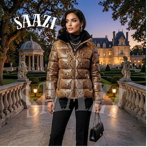 May include: A woman in a brown snakeskin-effect puffer jacket with a black fur collar and gold zip. She wears black trousers and carries a black handbag. The image includes the white text "SAAZI" at the top left. The background features a stately home.