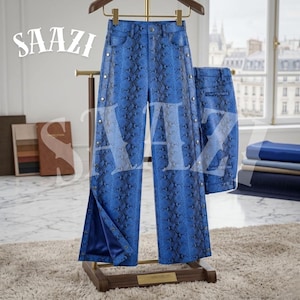 May include: Blue snake print trousers with snap fastenings and a matching jacket are displayed on a wooden hanger. The trousers have a wide leg design and are made of a textured material. The word "SAAZI" is printed on the top left corner.