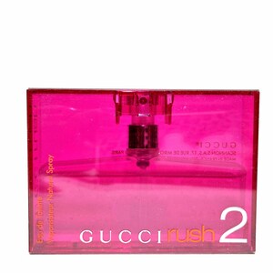 May include: A rectangular, transparent pink perfume bottle with a spray nozzle. The bottle has the words "GUCCI rush 2" printed on the front in white and orange. The words "Eau de toilette Vaporisateur Natural Spray" are printed on the side.
