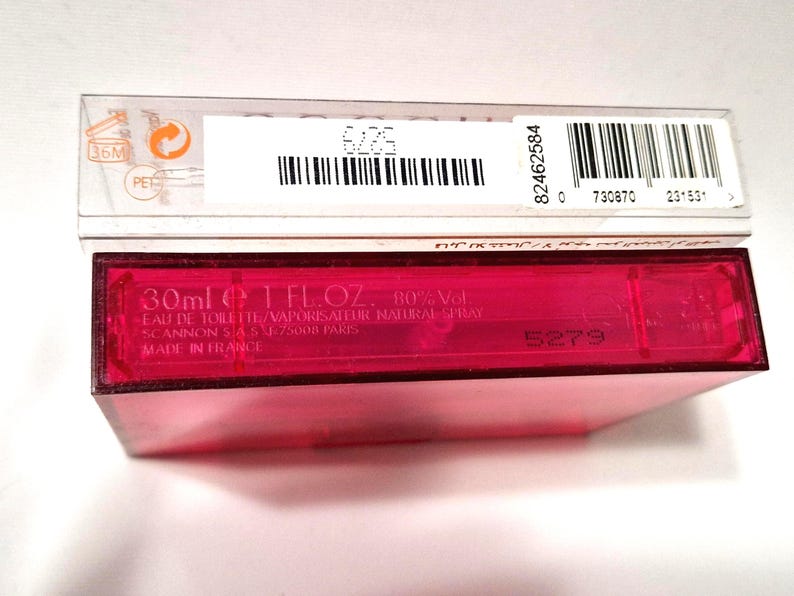 May include: A close-up of a pink rectangular perfume bottle with a clear plastic box on top. The bottle has the text "30ml 1 FL.OZ. 80%Vol." and "MADE IN FRANCE". The clear box has a barcode and the text "36M".