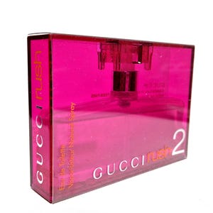 May include: A rectangular, transparent pink perfume bottle with a silver atomizer. The bottle is labelled "GUCCI Rush 2" in white lettering. The words "Eau de Toilette Vaporisateur Natural Spray" are also visible.