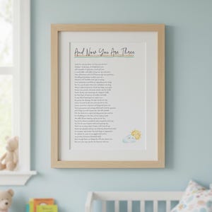 May include: A framed print with the text "And Now You Are Three" in a nursery. The artwork features a poem with a watercolor illustration of a sun and cloud. The frame is light wood, and the background is a light blue wall.