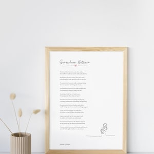 May include: A framed print with the title "Somewhere Between" in cursive script. The print features a poem with a heart symbol and a line drawing of a person. The frame is light brown, and the background is white.