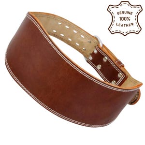 Può includere: Una cintura da sollevamento pesi in pelle marrone con cuciture bianche. La cintura ha una chiusura con fibbia e diversi fori di regolazione. L'immagine include una grafica che dice "GENUINE 100% LEATHER".