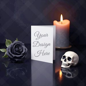 Könnte beinhalten: Eine weiße Grußkarte mit dem Text "Your Design Here" wird neben einer schwarzen Rose, einer brennenden Kerze und einem kleinen Schädel gezeigt. Die Gegenstände sind auf einer dunklen, reflektierenden Oberfläche angeordnet und erzeugen ein gotisches oder Halloween-Thema.