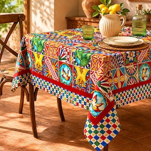 Puede incluir: Un mantel rectangular con un diseño de patchwork vibrante y multicolor que presenta motivos repetidos de limones, soles y pájaros. La tela muestra una cuadrícula de cuadrados rojos, azules, amarillos y verdes, rematada con un borde a cuadros.