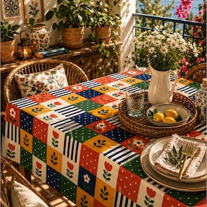 Puede incluir: Un mantel rectangular con un vibrante patrón de mosaico de cuadrados en rojo, amarillo, azul y verde. El diseño incluye lunares blancos, rayas azules y blancas, y motivos florales estilizados en rojo y blanco sobre una cuadrícula.