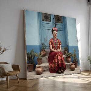 Puede incluir: Impresión enmarcada de una mujer con un vestido floral rojo y una corona de flores, sentada en escalones frente a una puerta azul. La imagen incluye plantas en macetas y un marco dorado, creando una exhibición artística.