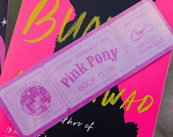 Pode incluir: Um marcador de livros rosa com o texto "Pink Pony Book Club" e um gráfico de bola de discoteca. O marcador de livros está em cima de um livro rosa com a palavra "BL" em amarelo. O texto "KEEP ON DANCING" também é visível.