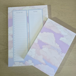 May include: Two notepads with a cloud design. One notepad has a "To do list" section and a "Notes" section. The other notepad has a cloud design. The notepads are light purple, blue, and white.