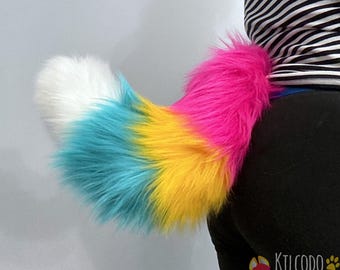 May include: A long, plush faux fur tail featuring a vibrant gradient pattern. The colors transition from a bright hot pink at the base, through a sunny yellow and a vivid turquoise, ending in a solid white tip. The tail has a thick, fluffy texture.