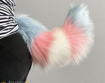 May include: A fluffy, long-haired faux fur tail featuring a color-blocked pattern of light blue, soft pink, and white sections. The tail is attached to a black garment and displays a thick, voluminous texture with a curved, tapered shape.