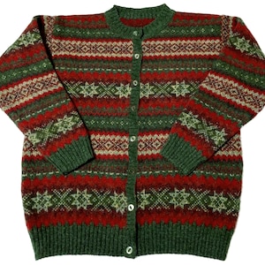 Pode incluir: Um casaco de malha de manga comprida com um padrão Fair Isle repetitivo em tons de verde floresta, vermelho profundo e creme. A peça apresenta um decote redondo, um fecho frontal com botões claros e punhos e bainha canelados.