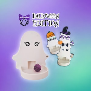 May include: A white ghost-shaped dice tower with a tray, featuring a purple polyhedral die. The text reads Roll Models HALLOWEEN EDITION. Two additional ghost figures are shown, one wearing a pumpkin hat and glasses, the other a witch hat.