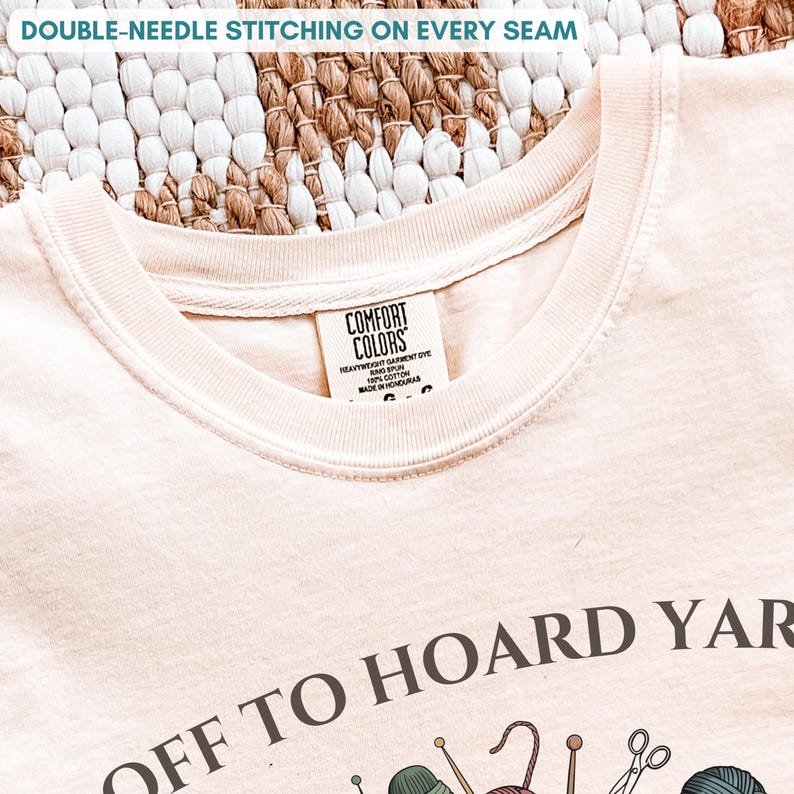 May include: Cream-colored t-shirt with the text "OFF TO HOARD YARN" and various yarn-related graphics. The shirt features double-needle stitching on the seams and a Comfort Colors label.