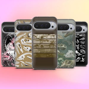 May include: A collection of phone cases with various dinosaur-themed designs. The cases feature illustrations of dinosaur skeletons, fossils, and prehistoric scenes in shades of brown, beige, and green. The cases are displayed against a gradient pink and yellow background.