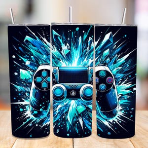 May include: A set of three stainless steel tumblers with a gaming controller design. The design features a blue and black color scheme with a controller graphic and a burst of blue shards. Each tumbler has a silver straw.