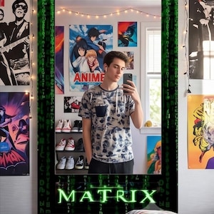 May include: A rectangular wall mirror featuring a black frame decorated with green digital code patterns and the word MATRIX in green text at the bottom. The mirror reflects a room with posters, a shelf of shoes, and a person holding a smartphone.