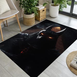 Może przedstawiać: Prostokątny czarny dywan z szczegółową ilustracją rogatego stworzenia z świecącymi pomarańczowymi oczami. Dywan ma mroczną, dramatyczną estetykę, odpowiednią do salonu lub sypialni. Projekt jest wyśrodkowany na dywanie.