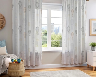 May include: White sheer curtains with a repeating pattern of hot air balloons in gray and tan. The curtains hang from a wooden rod in front of a window, with a view of a cityscape. The room also features a woven basket and a rug.