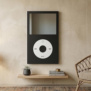 May include: A rectangular wall mirror featuring a black frame designed to resemble a digital music player. The upper portion is a reflective glass surface, while the lower section displays a white circular control interface with icons.
