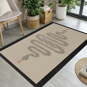 May include: A rectangular beige rug with a black border features a stylized snake design. The snake's body is composed of repeating black shapes, with a head and tail in red and green accents. The rug is placed on a tiled floor.