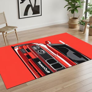 May include: A rectangular red rug featuring a stylized illustration of a red sports car. The car has black and white details, including the text "Tuner Cult". The rug is placed on a wooden floor.