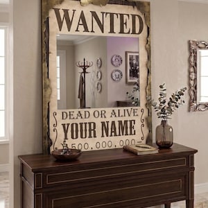 May include: A rectangular wall mirror featuring a distressed, metallic gold frame designed to resemble a vintage wanted poster. The mirror surface displays the text WANTED, DEAD OR ALIVE, YOUR NAME, and 500,000,000 in bold, dark brown lettering.