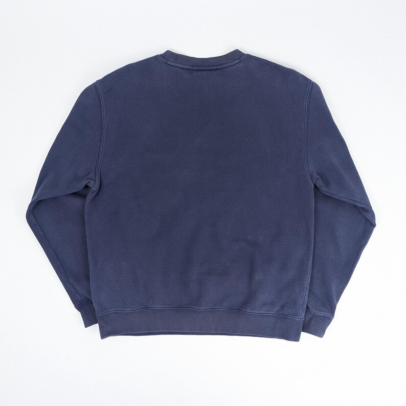 May include: A navy blue sweatshirt with a crew neck. The long-sleeved top is made of a soft material. The sweatshirt is a solid color and has a simple, classic design.
