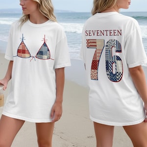 May include: A white short-sleeve t-shirt featuring a graphic of a bikini top with a red, white, and blue patchwork pattern on the front. The back displays the text SEVENTEEN above the large number 76 in a matching patchwork design.