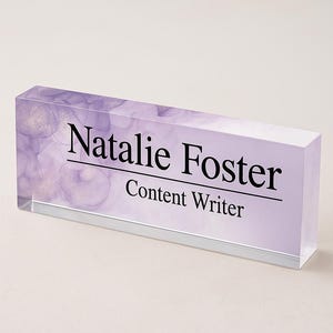Può includere: Targhetta da scrivania rettangolare con il nome "Natalie Foster" e il titolo "Content Writer" in nero. La targhetta ha uno sfondo lavanda con un design ad acquerello e una base argentata.