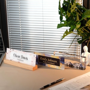 Peut inclure: Trois plaques de bureau avec noms et titres. L'une est dans un support en bois, les autres sont en acrylique transparent. Les plaques indiquent : Olivia Davis, Assistante ; Emily Johnson, Coordinatrice de projet ; et Michael Chen, Analyste financier.