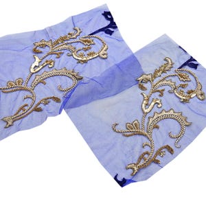 May include: Two pieces of sheer, light blue fabric with ornate gold embroidery. The embroidery features a scrolling floral design with intricate details. The fabric is slightly transparent, and the gold thread has a metallic sheen.