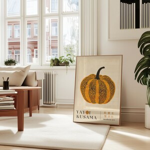 May include: A framed art print featuring a stylized pumpkin with a black stem and orange and black spotted pattern. The print includes the text "YAYOI KUSAMA" and Japanese characters, with "modern art" below.