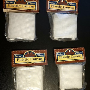 May include: Four packages of white plastic canvas squares, each labeled "Darice Plastic Canvas." The packaging includes the text "craft supplies" and "3 x 3" Square Plastic Canvas." Each package contains 10 pieces.