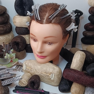 Może przedstawiać: Prezentacja produktów do stylizacji włosów, w tym peruk, grzebieni i spinek, z głową manekina pośrodku. Tekst po prawej stronie brzmi "Style your Hair Elevate Invisible Hairpadding". Peruki są w różnych odcieniach brązu, czerni i blondu.