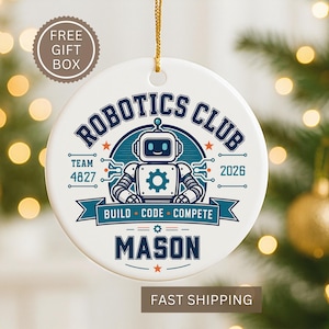 May include: A round white ceramic ornament featuring a blue and teal graphic of a robot. The text reads ROBOTICS CLUB, TEAM 4827, 2026, BUILD CODE COMPETE, and MASON. The ornament is suspended by a gold string and includes a circular badge stating FREE GIFT BOX.