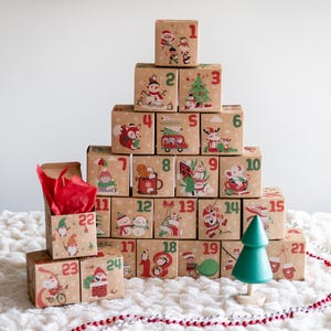 May include: A Christmas advent calendar made of numbered boxes, arranged in a tree shape. Each box features a festive illustration and a number. A small green wooden tree and a string of beads are also present.