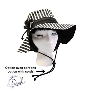 May include: Black and white striped sun hat with a black ribbon and a black bow. The hat has a wide brim and a chin strap with black cords.