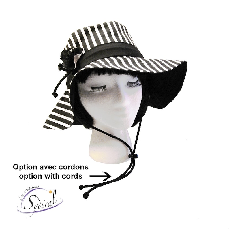 May include: Black and white striped sun hat with a black ribbon and a black bow. The hat has a wide brim and a chin strap with black cords.