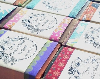 May include: Close-up of several wrapped soaps. Each soap is wrapped with a patterned band and a label with the text "From Aliese's Shower to Yours June 30, 2018" and a floral design. The bands feature various colors and patterns.