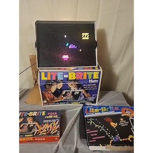 May include: A vintage Lite-Brite toy set with a black screen displaying colorful illuminated pegs. The set includes the original box, a refill kit, and a Looney Tunes picture refill. The box features children creating pictures with light.