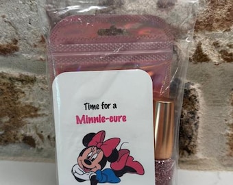 May include: A clear plastic bag containing a nail polish bottle and a white card. The card features a Minnie Mouse graphic and the text "Time for a Minnie-cure". The nail polish is a glittery rose color.