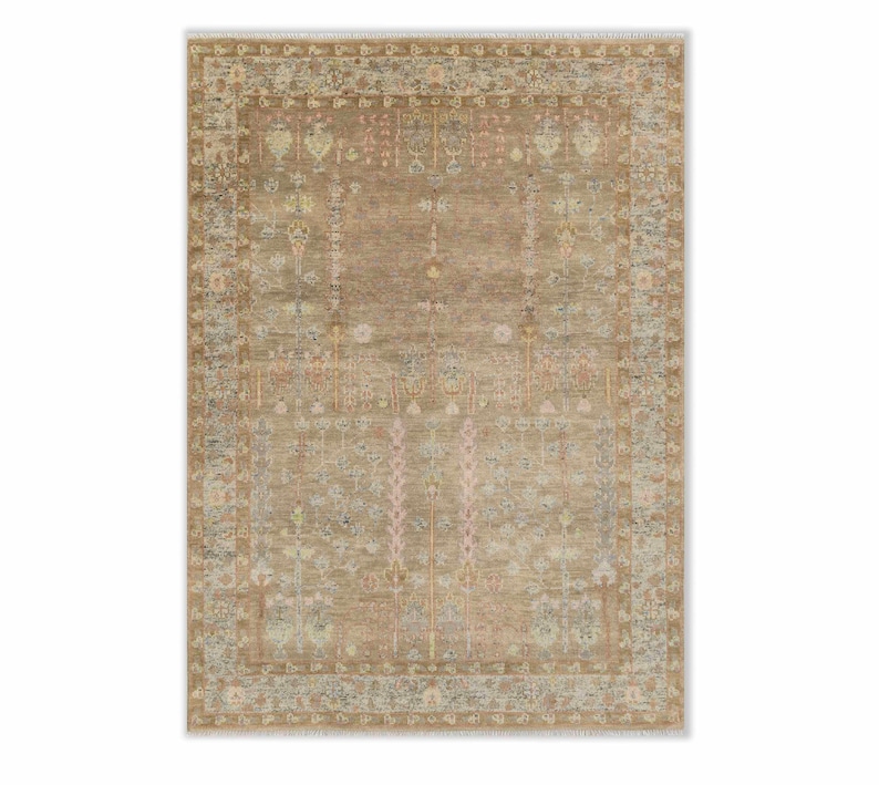 May include: A rectangular, beige area rug with an intricate, traditional design. The rug features a central field with floral and geometric patterns in shades of pink, blue, and yellow. The border has a detailed, repeating motif, and the rug has a fringe on the short ends.