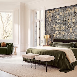 Puede incluir: Un dormitorio lujoso con una colcha de terciopelo verde oscuro, almohadas a juego y una manta color crema. Dos taburetes tapizados con patas de metal negro est&aacute;n al pie de la cama. Una gran tapicer&iacute;a floral cuelga sobre la cama.