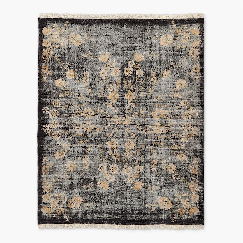Puede incluir: Alfombra rectangular de aspecto envejecido, con fondo gris oscuro y un estampado floral en beige y crema. La alfombra tiene un borde con flecos y un dise&ntilde;o central de medall&oacute;n floral.