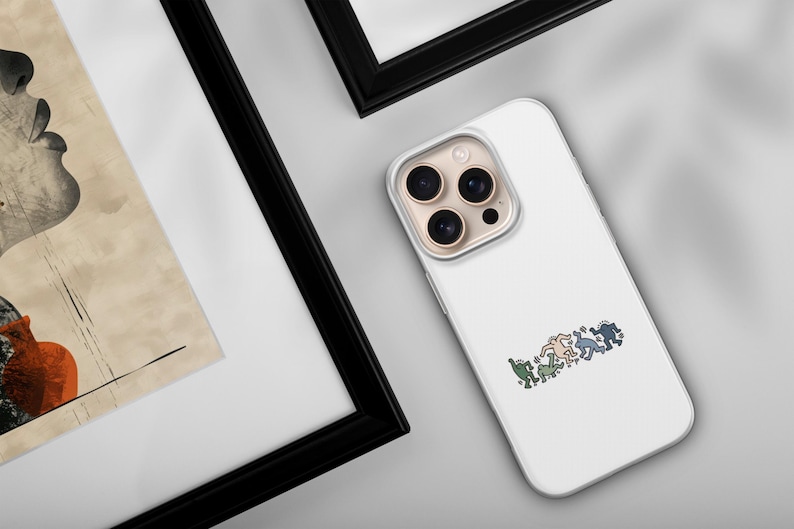 May include: White phone case with a colorful graphic of stylized figures in a row. The case has a clear border and a camera cutout. The image is on a light gray surface, with a framed artwork in the background.