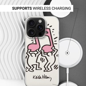 May include: A clear phone case featuring a Keith Haring design with a pink musical note and dancing figures. The case has a white background and the text "SUPPORTS WIRELESS CHARGING" and "SIDES ARE NOT PRINTED".