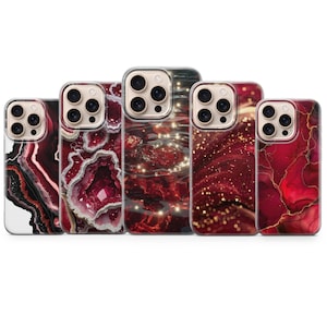 May include: A collection of five phone cases with unique designs. The cases feature a variety of red and white abstract patterns, including a geode-like design, swirling marble effects, and a starry night motif. The cases are designed to fit a smartphone.