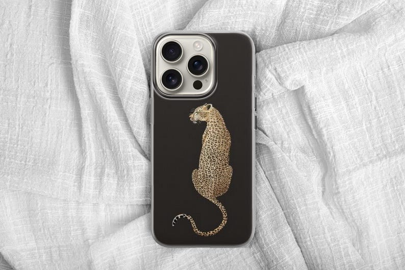 May include: A black phone case featuring a detailed illustration of a leopard. The leopard is depicted in a seated position with its tail curled, showcasing its distinctive spotted coat. The case has a clear border.